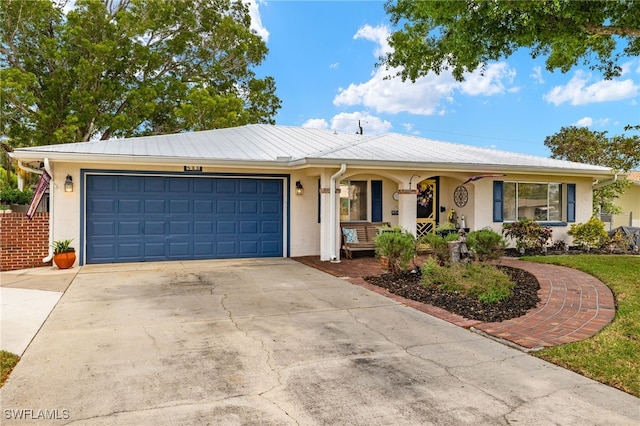 ranch-style house with stucco siding, covered porch, a garage, and concrete driveway