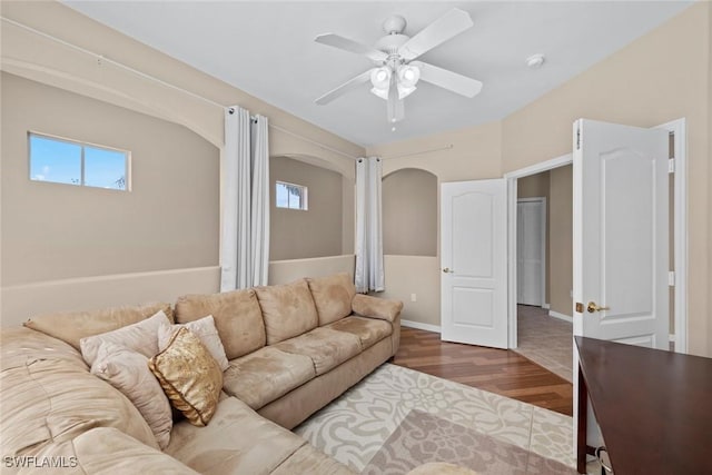 living area with wood finished floors, arched walkways, baseboards, and ceiling fan