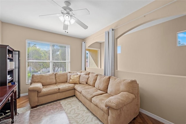 living room featuring baseboards, ceiling fan, and wood finished floors