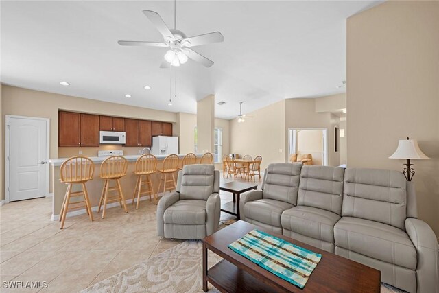 living room with baseboards, recessed lighting, a ceiling fan, vaulted ceiling, and light tile patterned floors