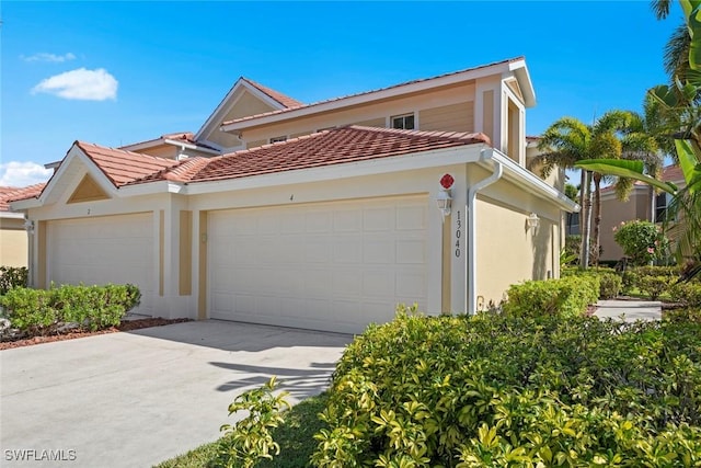 view of front of home with stucco siding, a tile roof, a garage, and concrete driveway
