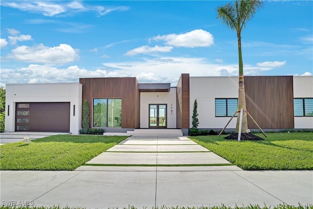 contemporary home featuring driveway, french doors, a front yard, a garage, and stucco siding