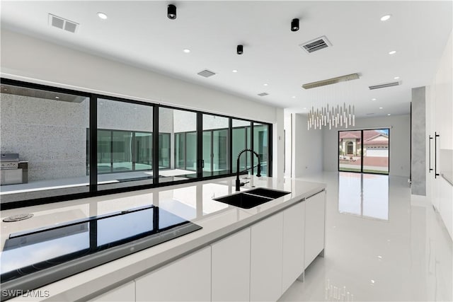 kitchen featuring white cabinetry, a sink, visible vents, and black electric cooktop