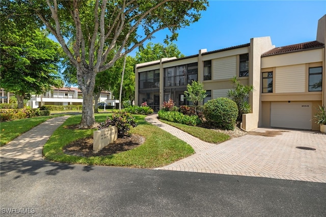 4855 Dockside Dr Unit 204, Fort Myers, FL 33919 - view of property featuring a garage, decorative driveway, stucco siding, and a tiled roof