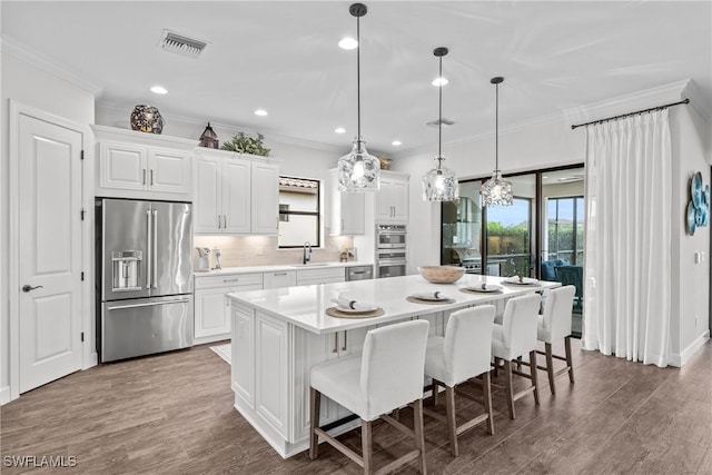 9476 Livorno Ct, Naples, FL 34119 - kitchen featuring high end refrigerator, crown molding, light countertops, a center island, and white cabinetry