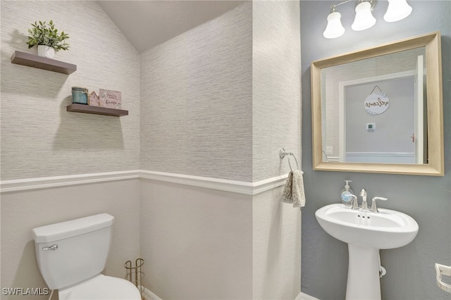 half bathroom with a sink, vaulted ceiling, and toilet