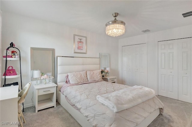 carpeted bedroom featuring two closets, a chandelier, and visible vents