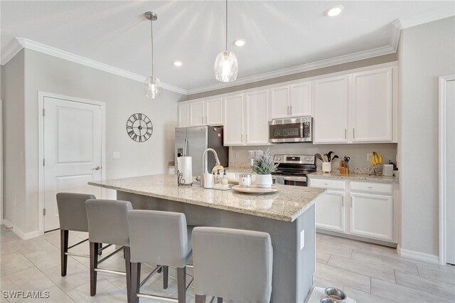 kitchen with crown molding, stainless steel appliances, a kitchen bar, and white cabinetry