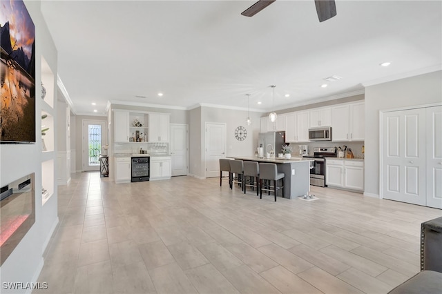 living area with beverage cooler, ornamental molding, ceiling fan, and recessed lighting