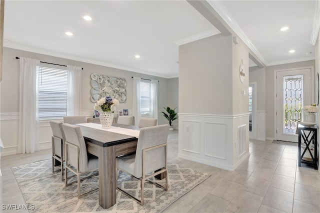 dining space with wainscoting, crown molding, and a decorative wall