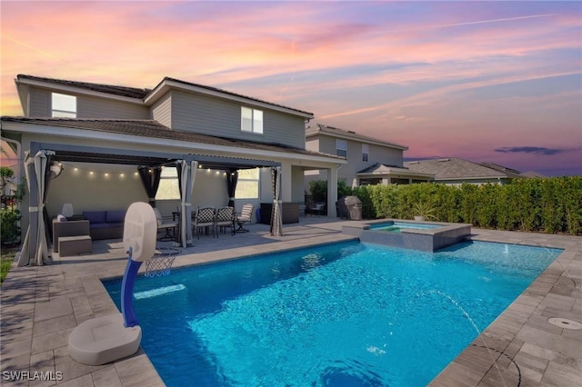 back of property at dusk with a patio area, a pool with connected hot tub, and an outdoor hangout area