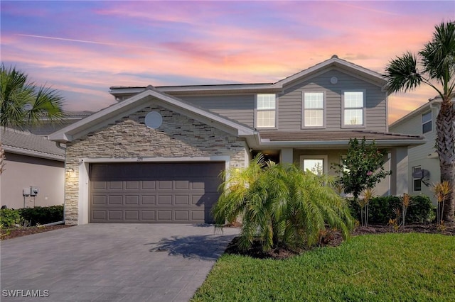 traditional-style house featuring a garage, driveway, and stone siding