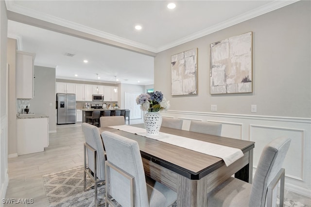dining area with recessed lighting, ornamental molding, wainscoting, and light wood-style flooring