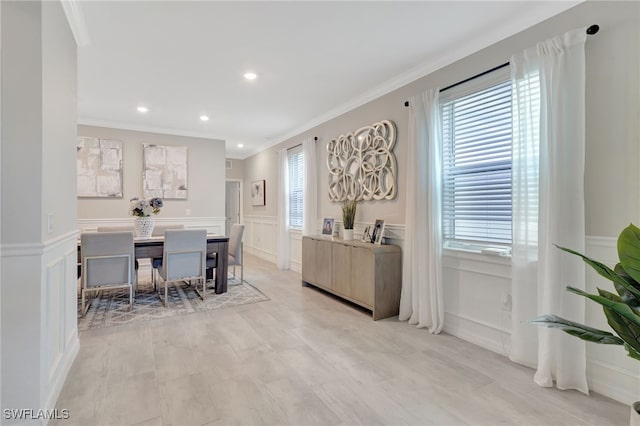 dining space featuring recessed lighting, ornamental molding, a wainscoted wall, and a decorative wall