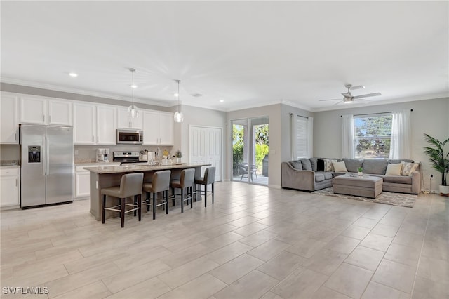 kitchen with a breakfast bar area, appliances with stainless steel finishes, an island with sink, and a wealth of natural light