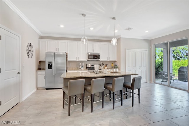 kitchen with a kitchen bar, appliances with stainless steel finishes, a center island with sink, light stone counters, and white cabinets