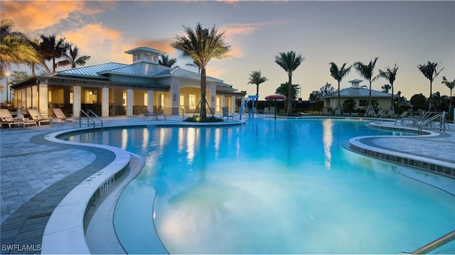 pool at dusk with a community pool and a patio area
