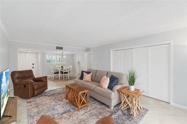 383 Harbour Dr Unit 209, Naples, FL 34103 - living area featuring light tile patterned floors, a textured ceiling, a chandelier, ornamental molding, and baseboards