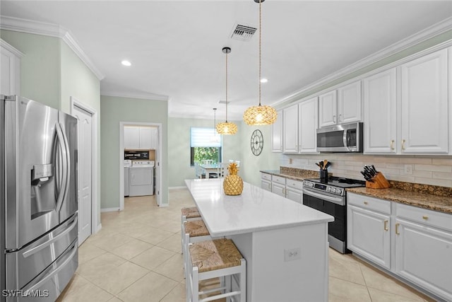 20374 Black Tree Ln, Estero, FL 33928 - kitchen featuring stainless steel appliances, washing machine and dryer, crown molding, light tile patterned floors, and decorative backsplash
