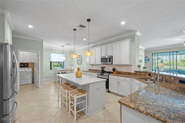 20374 Black Tree Ln, Estero, FL 33928 - kitchen with stainless steel appliances, washer / dryer, a sink, ornamental molding, and white cabinets