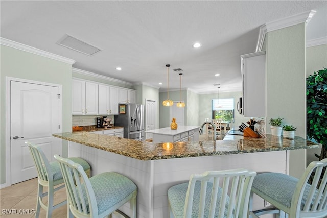 20374 Black Tree Ln, Estero, FL 33928 - kitchen featuring stainless steel refrigerator with ice dispenser, dark stone countertops, crown molding, a breakfast bar area, and a peninsula