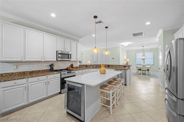 20374 Black Tree Ln, Estero, FL 33928 - kitchen with appliances with stainless steel finishes, beverage cooler, a peninsula, crown molding, and a kitchen breakfast bar