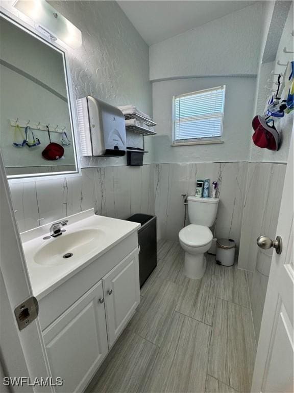 2618 35th Ave NE, Naples, FL 34120 - bathroom featuring toilet, a wainscoted wall, a textured wall, and vanity