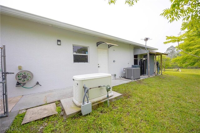 2618 35th Ave NE, Naples, FL 34120 - rear view of house featuring a lawn, central AC, and stucco siding