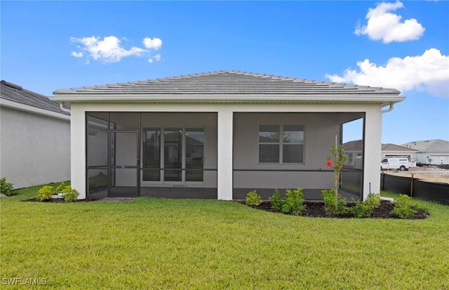 17313 Willow Tree Ln, North Fort Myers, FL 33917 - back of property featuring a sunroom, a lawn, a tile roof, and stucco siding