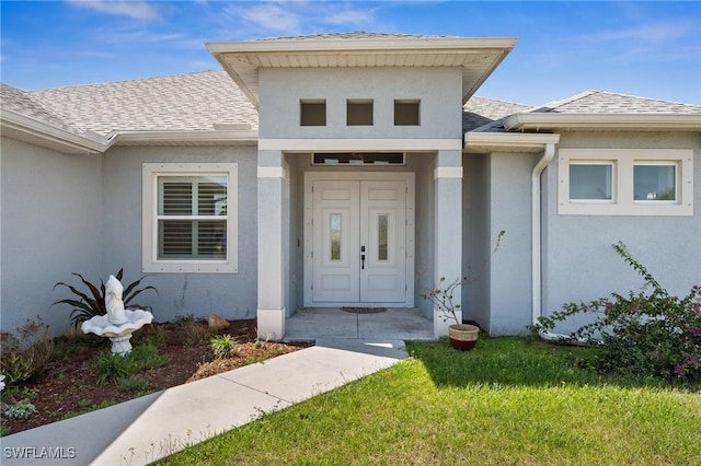 3407 20th St SW, Lehigh Acres, FL 33976 - view of exterior entry featuring a lawn, stucco siding, and a shingled roof