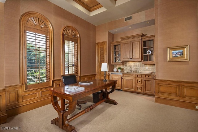 office area featuring a decorative wall, visible vents, wainscoting, and light carpet