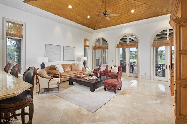 living area featuring crown molding, a raised ceiling, wood ceiling, a towering ceiling, and a ceiling fan