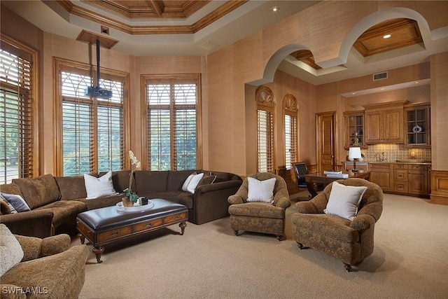 living room featuring coffered ceiling, a high ceiling, visible vents, ornamental molding, and carpet