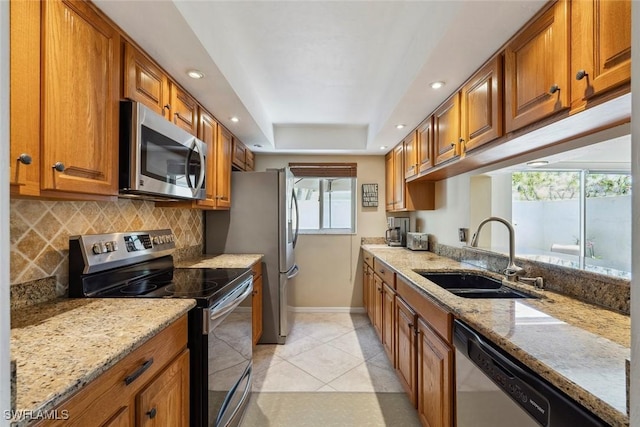 3130 Kings Lake Blvd Unit 7543, Naples, FL 34112 - kitchen featuring a sink, stainless steel appliances, a raised ceiling, brown cabinets, and backsplash