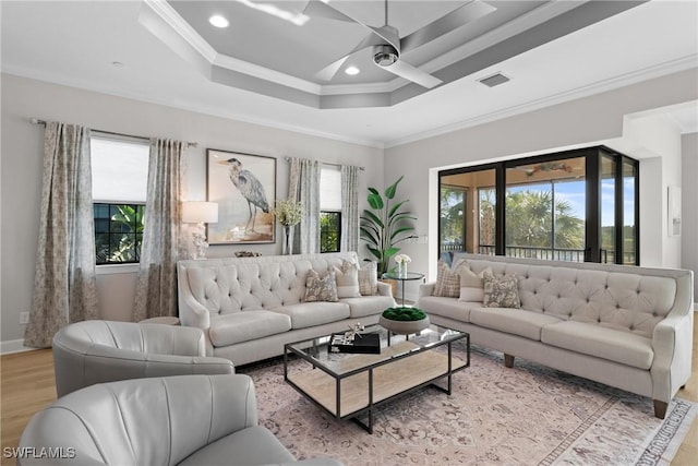 living area featuring a ceiling fan, ornamental molding, wood finished floors, recessed lighting, and a tray ceiling