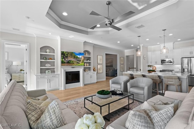 living room featuring crown molding, recessed lighting, ceiling fan, light wood-style flooring, and built in features