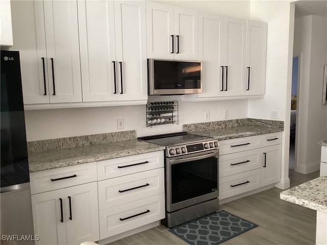 2939 Orange Grove Trl, Naples, FL 34120 - kitchen with appliances with stainless steel finishes, light stone counters, and white cabinets