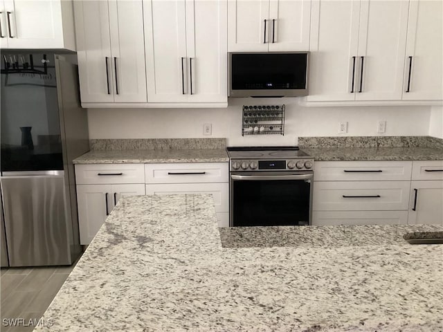 2939 Orange Grove Trl, Naples, FL 34120 - kitchen with appliances with stainless steel finishes, light stone countertops, and white cabinets