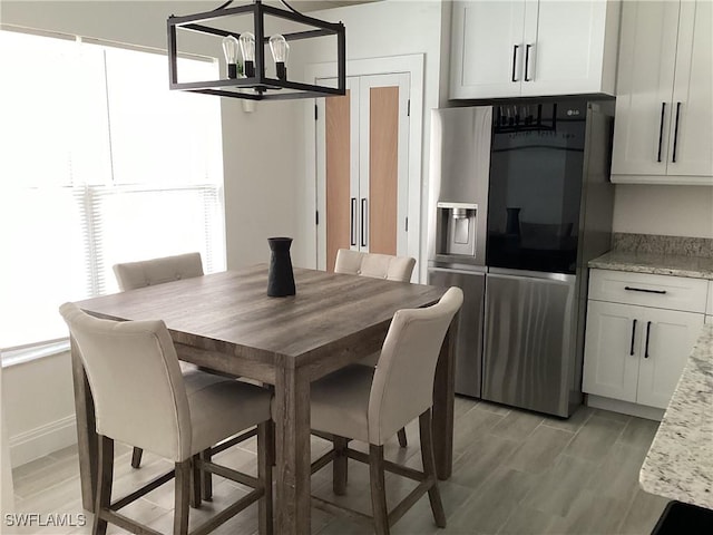 2939 Orange Grove Trl, Naples, FL 34120 - dining area featuring a chandelier, light wood-style flooring, and baseboards