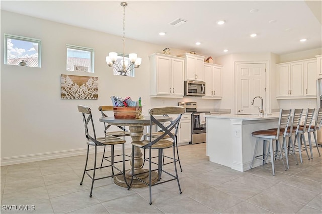 2916 Royal Gardens Ave, Fort Myers, FL 33916 - kitchen with an inviting chandelier, a kitchen breakfast bar, white cabinetry, recessed lighting, and appliances with stainless steel finishes