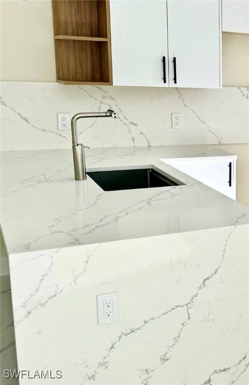 4800 Nora Ave N, Lehigh Acres, FL 33971 - kitchen view of decorative backsplash, light stone countertops, and open shelves