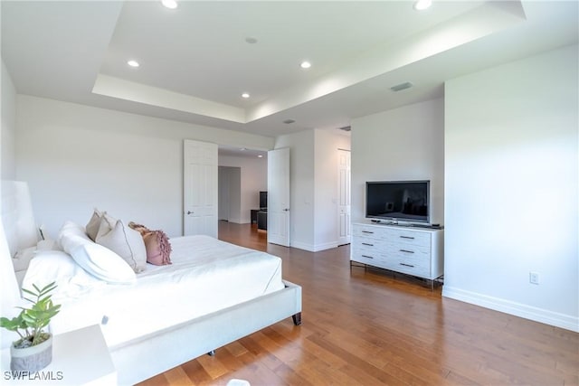 bedroom featuring visible vents, baseboards, wood finished floors, recessed lighting, and a tray ceiling