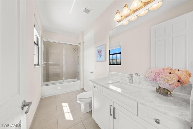 bathroom with toilet, vanity, tile patterned flooring, visible vents, and shower / bath combination with glass door