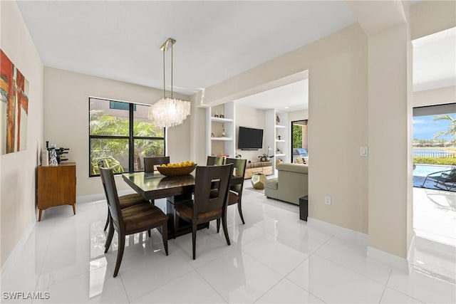 dining area featuring light tile patterned flooring, baseboards, a notable chandelier, and built in shelves