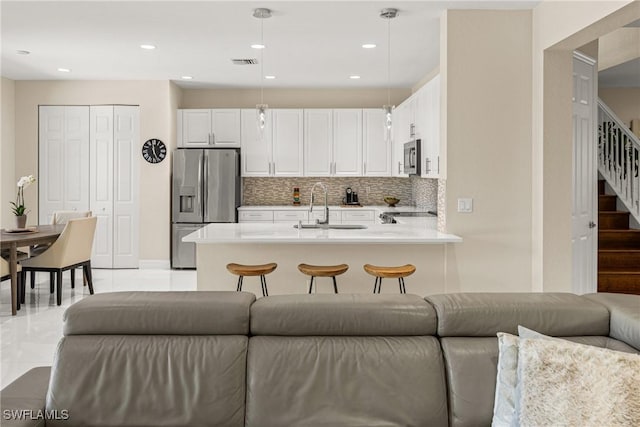 kitchen featuring open floor plan, light countertops, a sink, visible vents, and appliances with stainless steel finishes