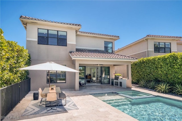 rear view of house with an outdoor kitchen, a tile roof, fence, and a patio area