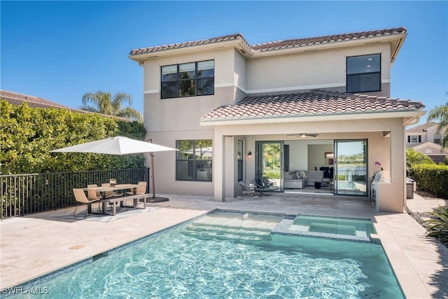 rear view of house with fence, a tiled roof, a pool with connected hot tub, stucco siding, and a patio area