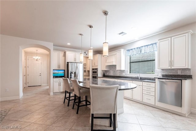 10870 Maitland Way, Fort Myers, FL 33913 - kitchen featuring appliances with stainless steel finishes, a sink, backsplash, arched walkways, and a breakfast bar area