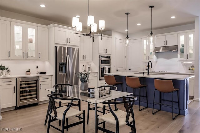 13005 Pembroke Dr, Naples, FL 34105 - kitchen featuring light countertops, appliances with stainless steel finishes, under cabinet range hood, a sink, and beverage cooler