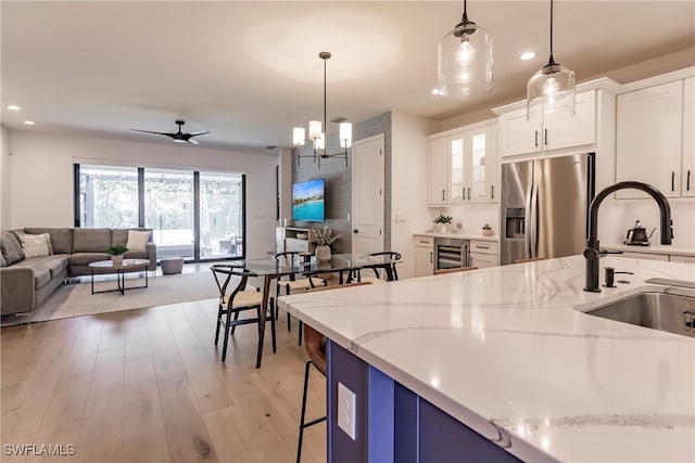 13005 Pembroke Dr, Naples, FL 34105 - kitchen with light stone counters, wine cooler, a sink, stainless steel fridge, and open floor plan